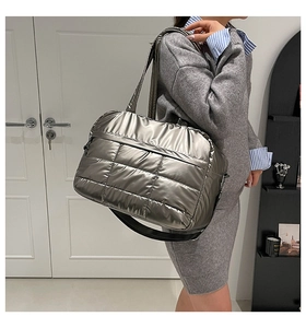 Detail of silver metallic quilted tote bag with adjustable black shoulder strap for commuting