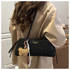 Close-up of black leopard print shoulder bag with plush bear charm and woven cord detail