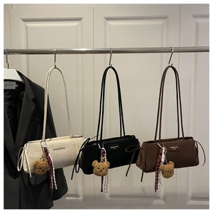 Three minimalist tote bags in beige black and coffee with bear charms on display