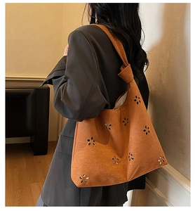 Détail d'un sac cabas en daim caramel avec motifs fleurs ajourés et bandoulière nouée