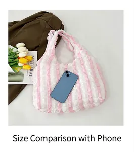 Close-up of pink and white striped puffy tote bag with a phone for size reference