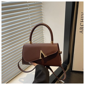 Detail of dark brown leather handbag with unique asymmetrical flap and gold clasp