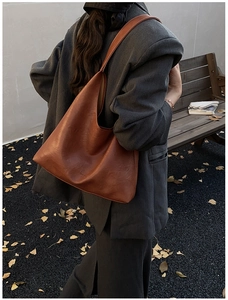 Brown vintage large leather tote bag with embossed letters shown on a model's shoulder
