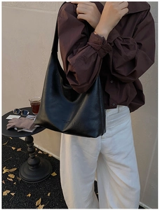 Detail of a large black leather tote bag featuring elegant lettering and relaxed Hobo design