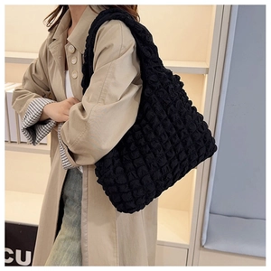 Side view of black bubble texture tote bag on model wearing khaki coat for daily commute