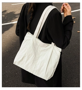 Detail of white wrinkled nylon tote bag featuring TIDE COCO logo patch and shoulder straps