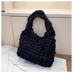 Close-up of the black bubble texture fabric and shoulder strap on a quilted tote bag