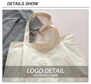 Detail shot of the beige leather logo patch on a white textured nylon tote bag