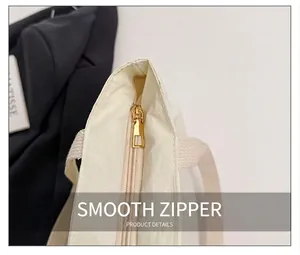 Detail of a smooth golden metal zipper on a premium off-white nylon tote bag close-up