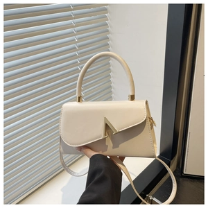 Detail of white leather evening bag with golden V-shaped hardware and top handle