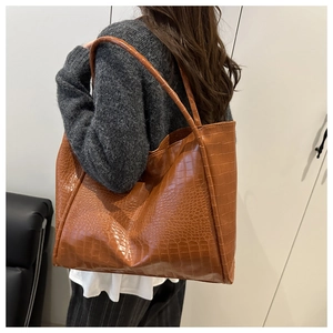 Brown crocodile pattern tote bag shown from side back view on model for size reference
