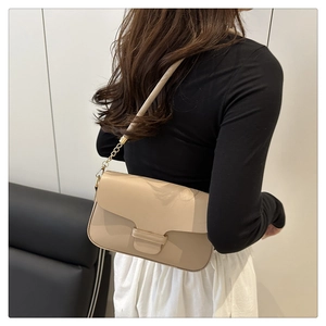 Chic beige leather shoulder bag with golden chain strap on a minimalist studio model
