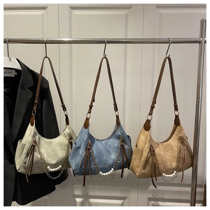 Close-up of hobo bag details with vertical zipper, pearl chain, and adjustable strap