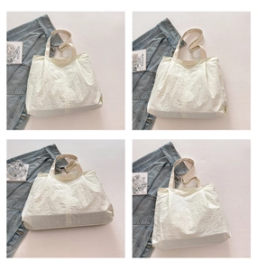 Detail of cream white pleated nylon tote bag showing lightweight fabric and textured handle