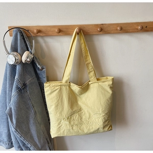 Gros plan détaillé des broderies sur un sac cabas jaune clair en tissu nylon de qualité