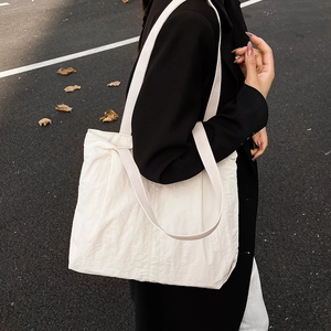 Minimalist large white canvas tote bag for women showing crossbody style on a model
