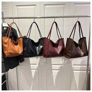Croc-embossed tote bags in orange, black, burgundy, and brown colors hanging on hooks