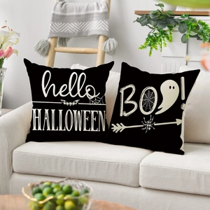 Close-up of black Halloween pillow covers with ghost and spider prints on a white sofa