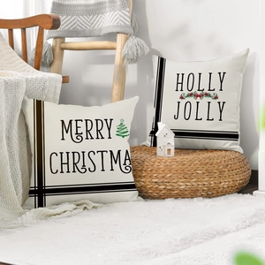 Close-up of two beige Christmas pillow covers with festive lettering on a cozy white rug