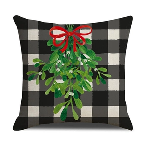 Close-up of buffalo plaid Christmas pillow cover with mistletoe and red bow design