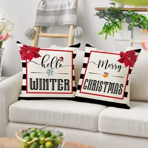 Detail of two Christmas pillow covers with Poinsettia prints on a cozy fabric sofa