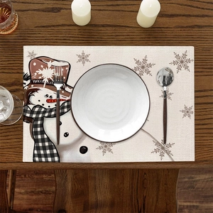 Close-up of linen Christmas placemat with snowman pattern on dark wood dining table
