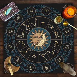 Detail of tarot tablecloth featuring golden zodiac symbols and celestial moon sun pattern