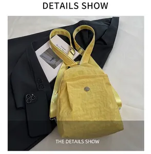 Close-up of bright yellow nylon chest bag with round metal logo on a black background