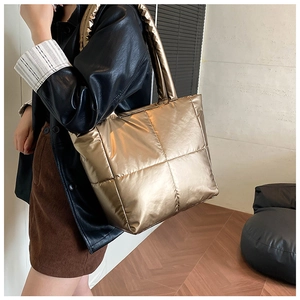 Close-up of champagne gold quilted tote bag with large square stitching and glossy finish