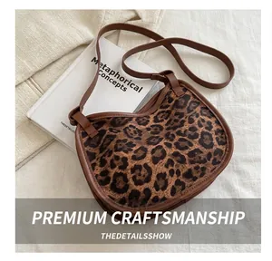 Close-up of leopard print tote bag with brown leather trim and fine stitching detail