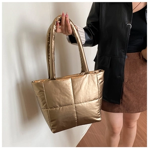 Detail view of metallic gold quilted tote bag with large square stitching and puffy texture