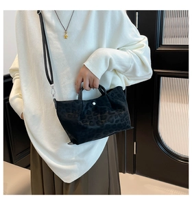 Detail of leopard print tote bag with suede texture, black handles and long shoulder strap