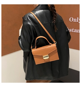Détail du sac bandoulière marron clair avec boucle dorée et texture cuir lisse
