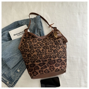 Macro detail of leopard print shoulder bag with brown leather trim and denim accents