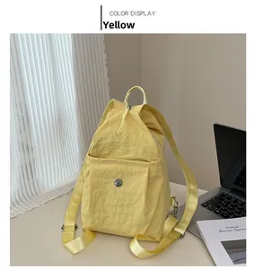 Detail view of yellow lightweight nylon backpack with drawstring and metal logo on desk