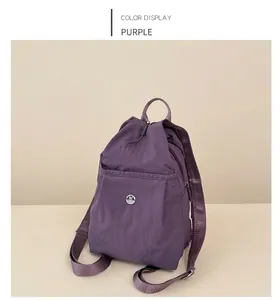 Detail of purple nylon backpack with circular metal M logo and adjustable straps