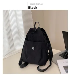 Detail of black nylon backpack featuring a metal logo on desk with a laptop
