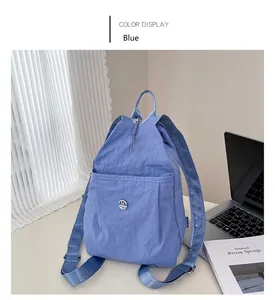 Detail of blue waterproof nylon backpack with zipper pocket and metal logo on white desk