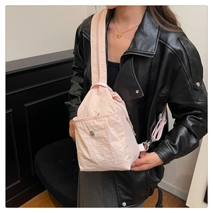 Detail of light pink nylon crossbody bag showing the premium texture and metal logo