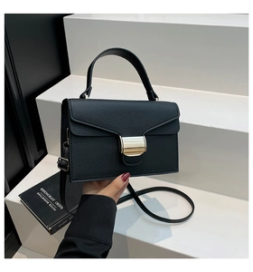 Vue détaillée du sac à main noir en cuir grainé avec une large boucle métallique dorée
