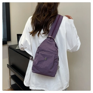Detail of dark purple nylon crossbody bag with adjustable strap worn by a model