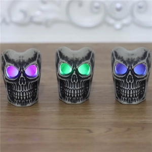 Three Halloween LED skull candle lights with glowing eyes in purple, green and blue colors