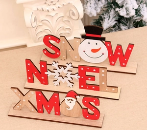 Dettaglio di decorazioni natalizie fai da te in legno con scritte SNOW e NOEL e motivi dipinti