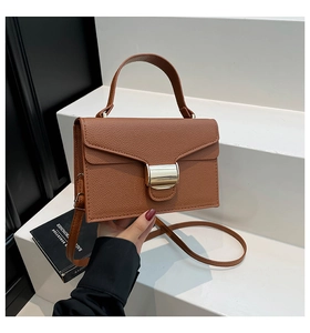 Détail de la texture cuir grainé marron et du fermoir rectangulaire en métal doré chic