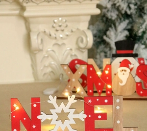 Dettaglio di decorazioni natalizie in legno dipinto XMAS e SNOW con Babbo Natale e pupazzo