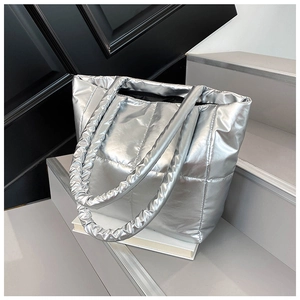 Detail of silver quilted tote bag with metallic finish and thick padded top handles