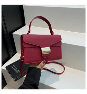 Détail du sac à main rouge foncé en cuir grainé avec boucle dorée et bandoulière