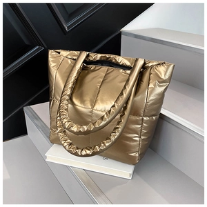 Macro detail of golden quilted puffer tote bag fabric with metallic finish and top zipper