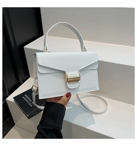Détail d'un sac à bandoulière en cuir blanc grainé avec boucle et poignée dorées