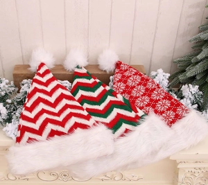 Close-up of three knitted Christmas hats with plush pom-poms on a rustic mantelpiece